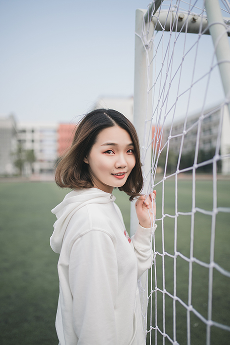 A female posing in front of goal posts 