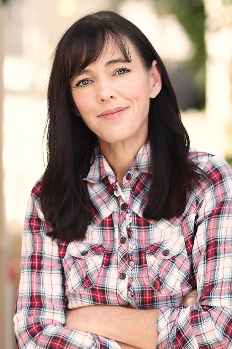 An outdoor portrait of a brunette woman in checked shirt