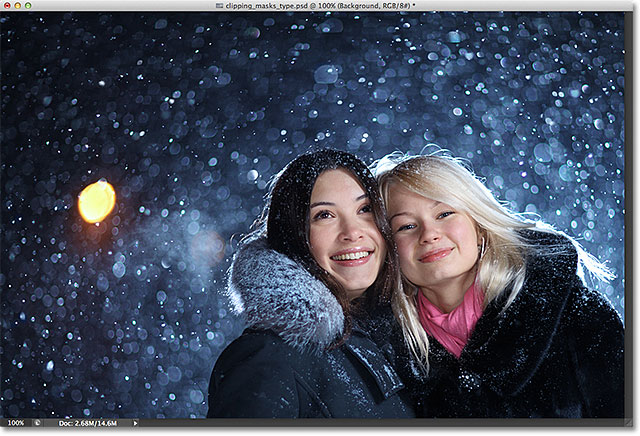 Two happy young female friends enjoying snowfall on Christmas winter night over snow background. Image licensed from Shutterstock