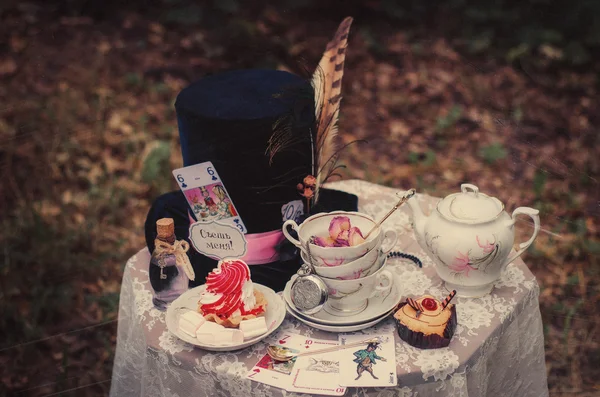 Hat, hatter, pen, tea party, Alice in Wonderland, Through the Looking-Glass, fairy tale, fantasy, scenery, eat me, drink me, candy, bubble, liquid, magic potion, table, tablecloth, lace, saucer, tea, tea, cup, dried roses, spoons, lens Stock Photo